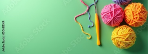 Colorful yarn balls and crochet hook on green background.