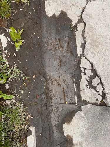 Old asphalt road in need of repair. Damaged asphalt in patches and cracks. Mud on the road after rain.