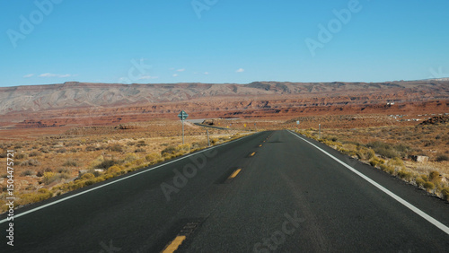 Pov from car driving on empty highway. Riding on intercity asphalt road in desert prairie background of red rock massif with hills west USA. Cargo transportation delivery goods or travel roadtrip