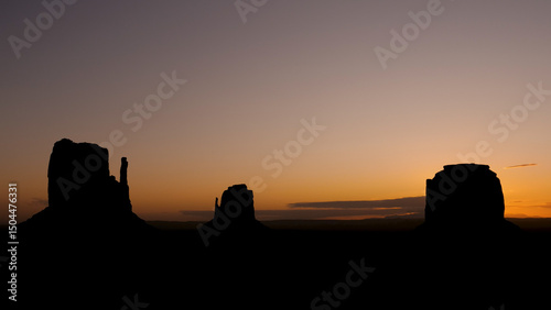 Timelapse of morning bright colorful sunrise in monument valley national indian park desert in western Usa. Dark silhouettes of three famous massive sandstone rock buttes on sun lights daybreak.