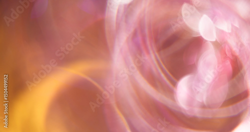 Swirling circle. Defocused radiance. Multicolored pink yellow lens flare on blurred bokeh light abstract background.