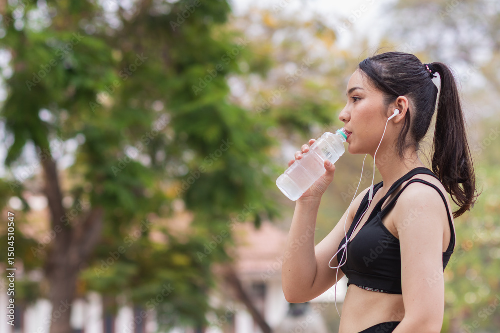 Portrait of beautiful Asian runner drinking water from plastic bottle because she feels tired from run and wants take break drink water. Beautiful Asian woman taking break drink water after tiring run Portrait of beautiful Asian runner drinking water from plastic bottle because she feels tired from run and wants take break drink water. Beautiful Asian woman taking break drink water after tiring run