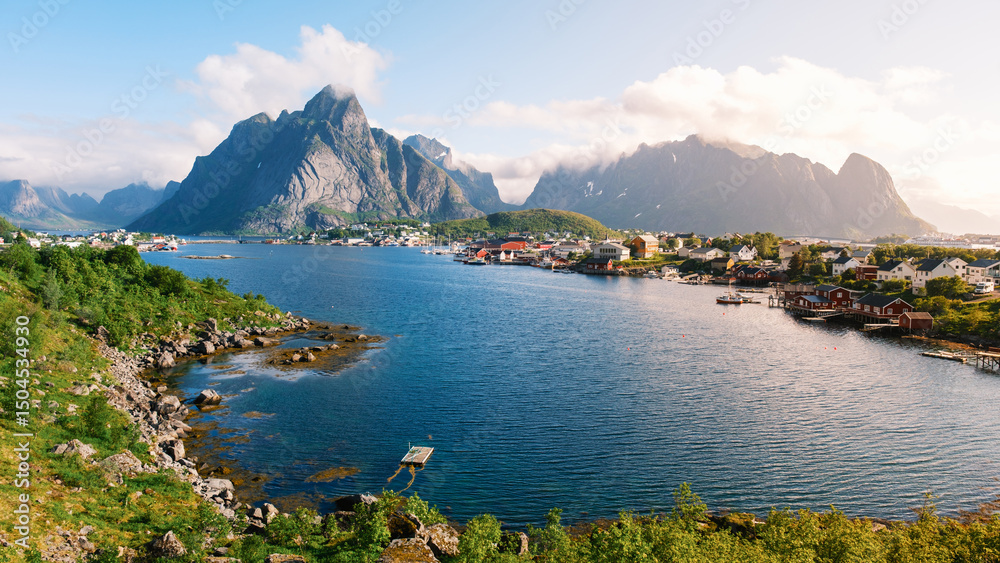 Fototapeta premium Majestic mountains rise above a tranquil fjord in Norway, with quaint fishing cabins nestled along the shoreline. Reine Lofoten Norway