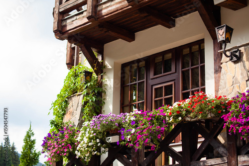 the wooden balcony is decorated with numerous multi-colored flowers.