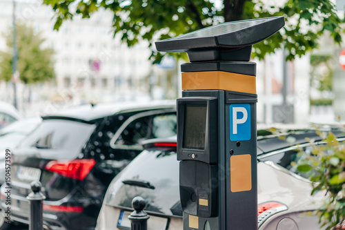 Fototapeta Naklejka Na Ścianę i Meble -  A solar-powered parking meter positioned beside parked vehicles in a bustling city setting, showcasing modern parking technology and convenience
