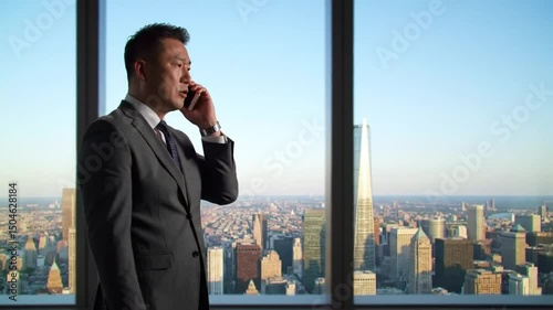 Businessman talking on phone with city skyline view from high rise window