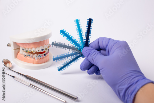 Orthodontic color samples held by gloved hand with dental model in background. photo