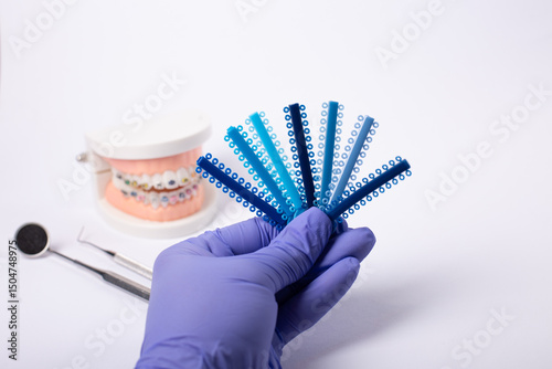 Orthodontic color samples held by gloved hand with dental model in background. photo