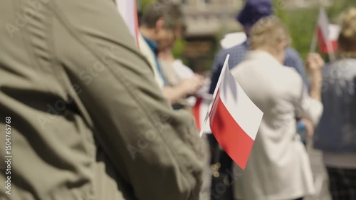 Close-up of a participant holding a small Polish flag during a peaceful protest. Symbol of national pride, unity, and civic engagement. Ideal for political, social, and documentary content.