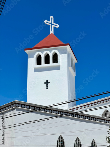 White church dome with a cross on top and a beautiful deep blue sky in the background
