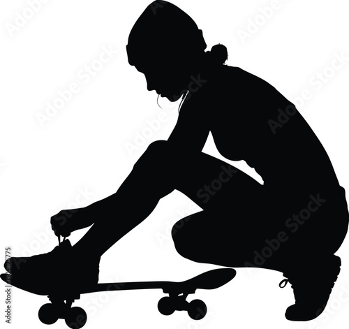 Young woman skateboarder silhouette crouching tying shoe
