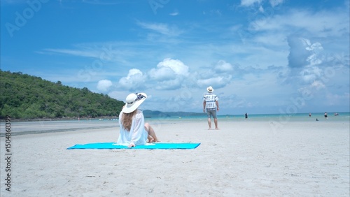 Young couple on vacation on a white sandy beach, clear sky and sea