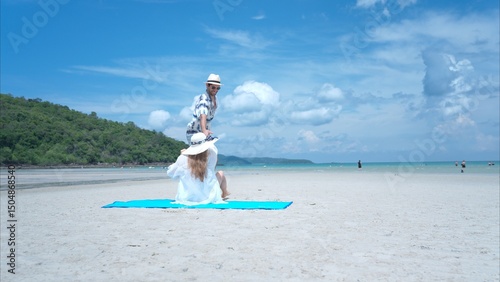 Young couple on vacation on a white sandy beach, clear sky and sea