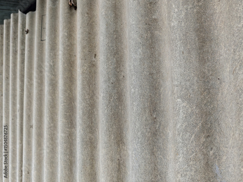 Detailed shot showcasing the rhythmic texture and undulation of weathered, corrugated material. The play of light and shadow accentuates its ridged form, lending a raw and industrial feel.