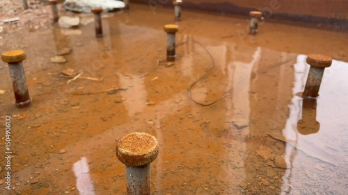 Rust-Covered Steel Platform with Capped Studs and Surface Water