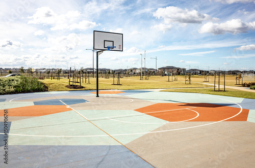 Modern outdoor basketball court with colorful painted surface designs and court markings. A well-maintained recreational or sports facility in an Australian suburban residential neighborhood