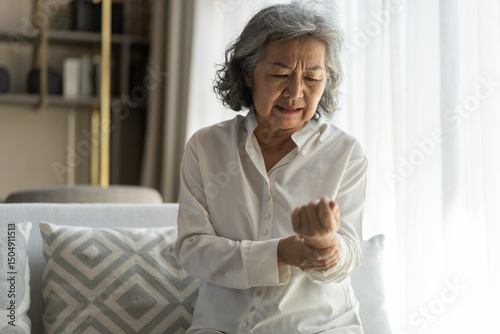 Wallpaper Mural Elderly asian woman holding wrist pain, arthritis, health issue, senior female suffering from joint pain at home, expressing discomfort, aging health problem, chronic condition indoor living room Torontodigital.ca
