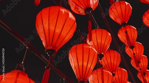 Glowing red lanterns softly swinging, casting warm light against shadowy background, highlighting festive asian cultural celebration