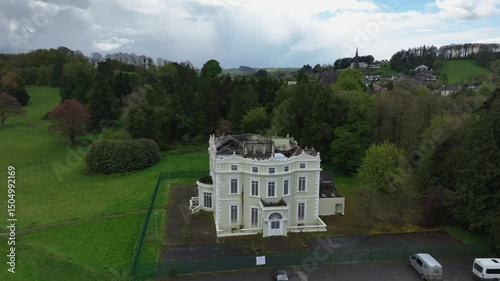 Hope Castle, County Monaghan, Ireland, September 2022. Drone orbit approach descend clockwise to front angled facade and entrance of building with fence protecting and keeping vandals out.