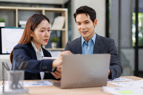 Team of Asian business people point to graphs and charts to analyze market data, balance sheet, account, net profit to plan new sales strategies to increase production capacity.
