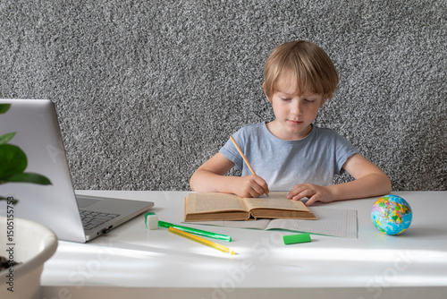 Child engaged in remote learning at home with a laptop and book