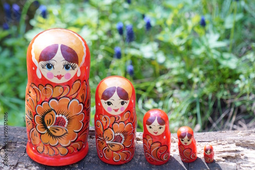 Wooden nesting dolls stand in a row in the forest.
