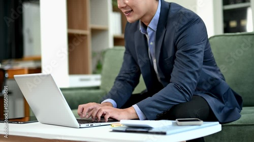 Closeup of businessman in suit multitasking with smartphone and laptop at desk. workspace concept