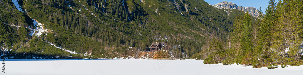 Frozen Sea Eye lake in Tatra mountains with wooden shelter. Poland