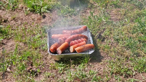 Tasty Fat Dripping Sausages Grilled on Disposable Single Use Portable Charcoal Grill