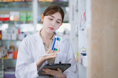 Pharmacist checking stock of drug on shelves with digital tablet in the pharmacy drugstore