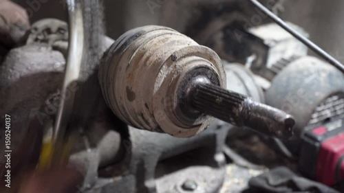 car  half axle repair, auto mechanic cleans a car axle from mud, car axle secured in a vice, repair in a garage