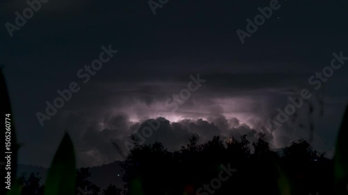 Multiple Lightning Strikes Illuminate Towering Thunderclouds Above Mountain Range at Night on a Tropical Island in Continuous Time-Lapse Sequence