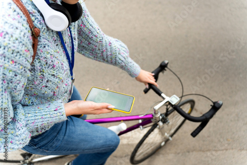 University student using smartphone while riding bicycle on campus