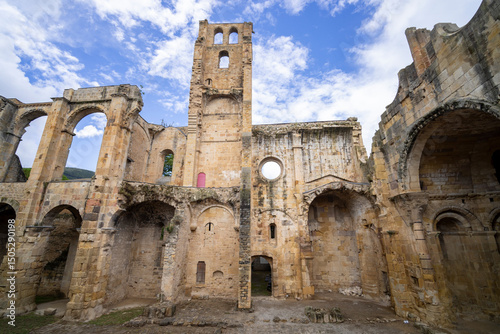 Ruins of the Abbey of Sainte Marie in Alet les Bains, showing remaining walls and arches under blue sky
