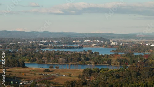 Distant view along Lake Burley Griffin towards the CBD with notable Canberra landmarks visible, framed by autumn colours and light.