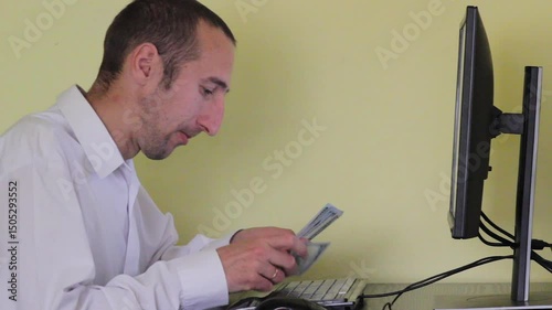 Businessman counting money while sitting at a computer, earning money on computer, work online, counting money