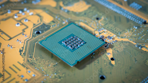A computer chip is shown on a circuit board. The chip is green and has a lot of small holes