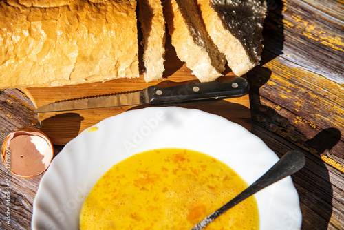 Scrambled eggnand  in a white plate and old bread on a wooden table, kitchen theme.
