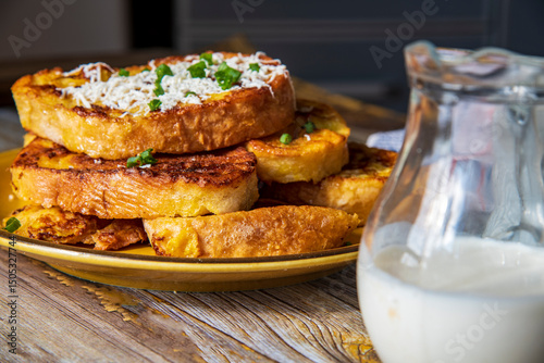 Fried bread with egg and milk cream or white cheese on top on a wooden table.