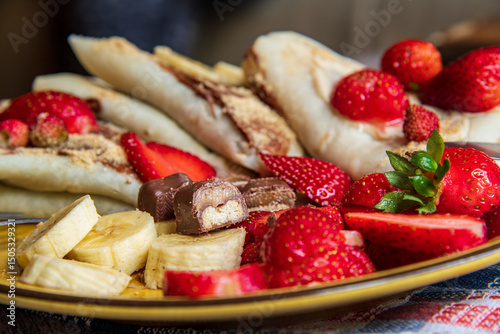 Pancakes, crepes with chocolate, fresh strawberries and banana 