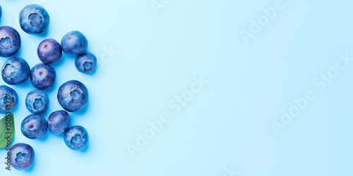 Fresh blueberries with green leaves flat lay on light blue background. Healthy berry and nutrition concept. Image for banner with copy space.