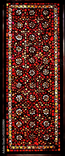 Symmetrical design of concentric circles in red, orange, yellow, and white with delicate floral decoration on a window