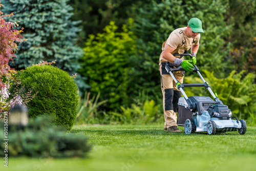Man Mowing Grass in a Lush Garden on a Sunny Day With Vibrant Greenery and Well-Maintained Plants