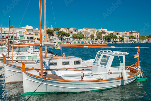 Traditional boats in the harbor of Portocolom with the old town in the background - 3104