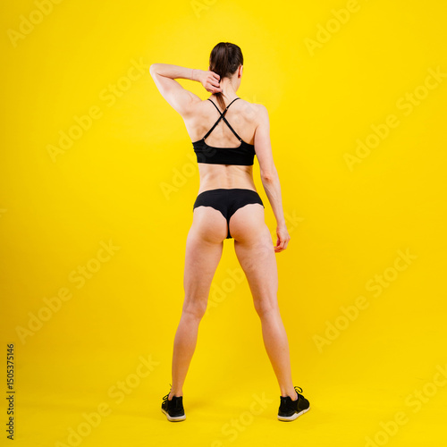 Fit sportswoman in leggings and sports bra looking away and while standing on yellow red
