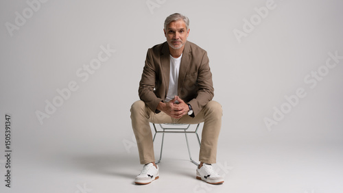 Schilderij op canvas Happy middle aged business man sitting in chair isolated on white background