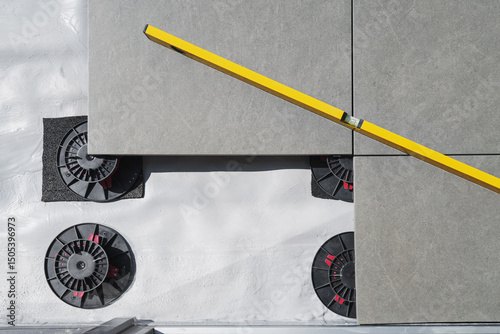 Laying tiles concept. Tiler, spatula and glue when laying tiles with close up hands. Stilts and pedestal supports for ceramic tiles to be laid on the terrace or balcony - leveling system.