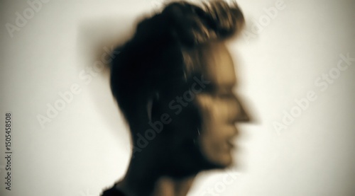 Blurred Portrait of a Person with Stylish Hair in Dark Tones Against a Plain Background