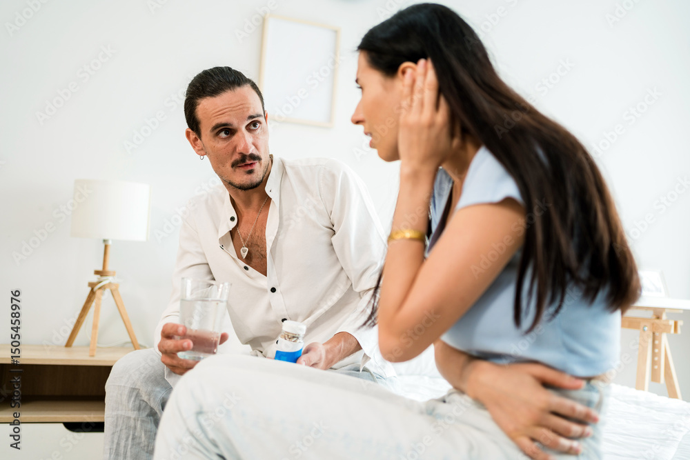 Obraz premium Concerned man offers medicine and water to his partner experiencing PMS symptoms. A tender indoor scene of care and support, ideal for health, wellness, and relationship-related content.