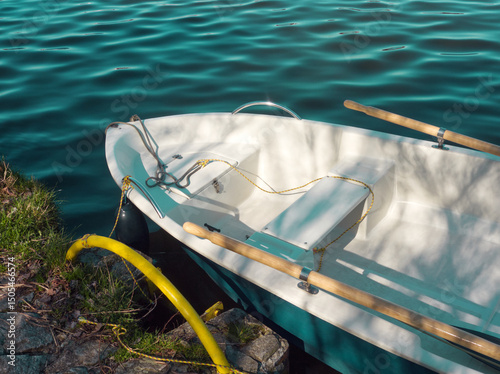 Boat background. White boat with paddles (oars) on blue water. Blue water background. View of small paddle boat floating on river Spree, Berlin Vintage boat in harbor. Landscape. Water landscape. Row